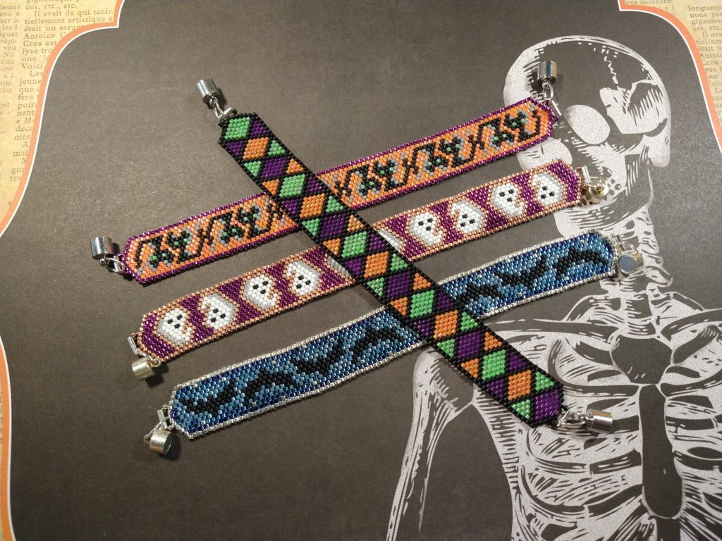 Four beaded Halloween bracelets on a spooky skeleton paper.