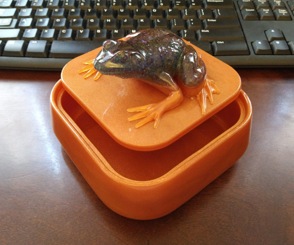 Orange resin box with a frog on top.