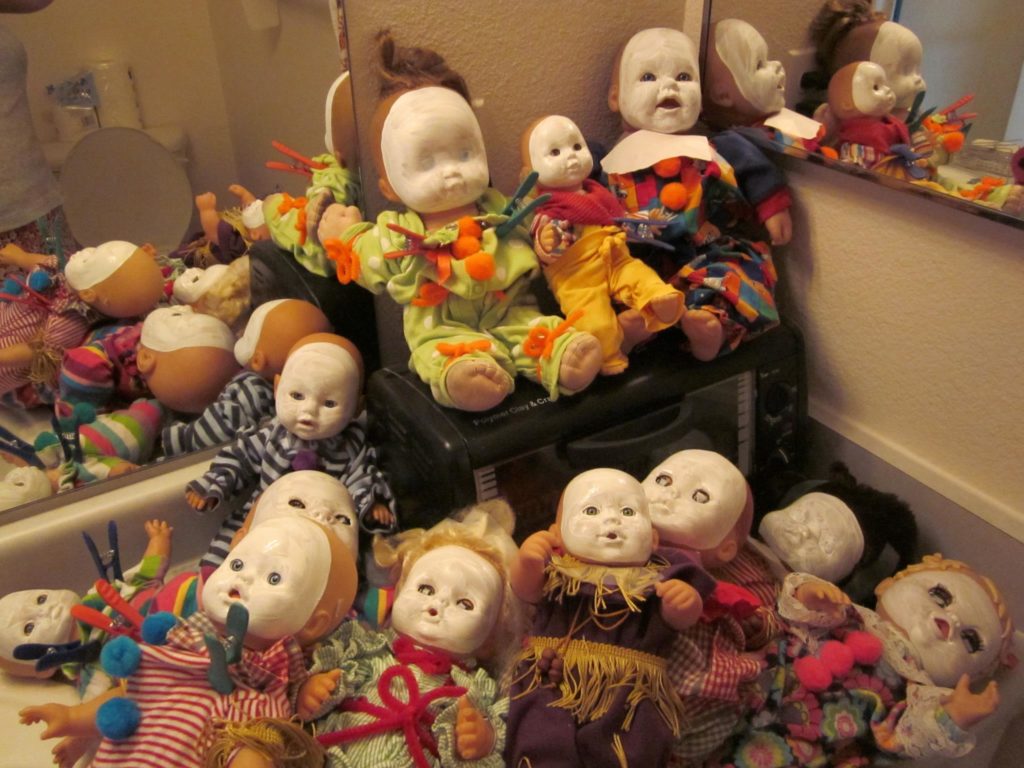 A bunch of dolies with white faces and clown outfits.