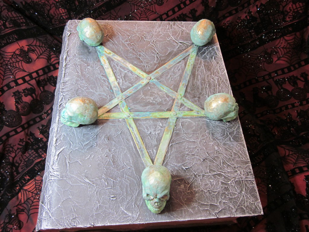 Large, evil book from the top, sporting a pentagram with skulls at the points.