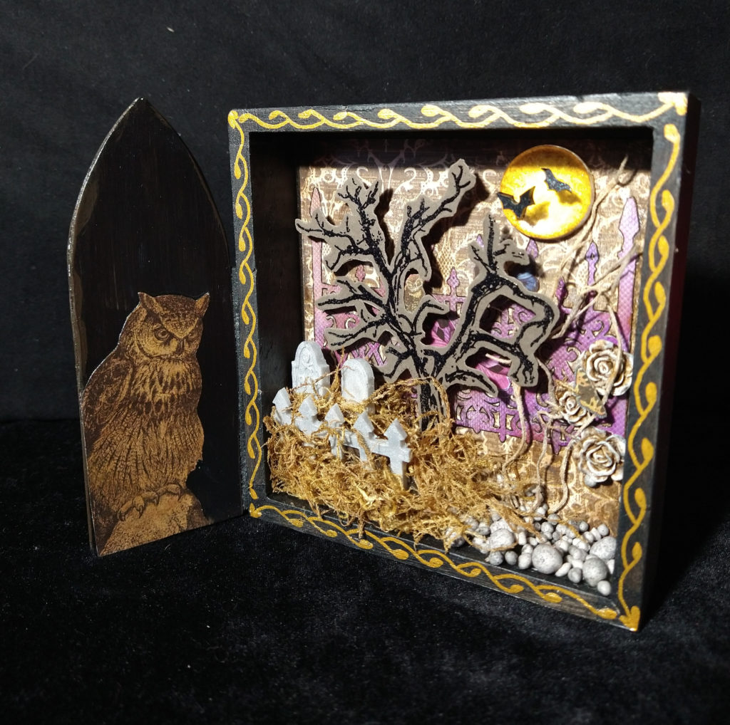 Open cemetery shadowbox, with an owl inside the gate.
