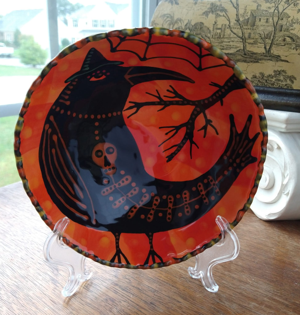 Orange and black bowl with a crow who has a skeleton in his belly.