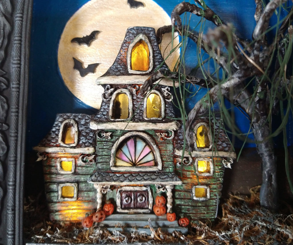 Closeup of tiny haunted house with lights in the windows.