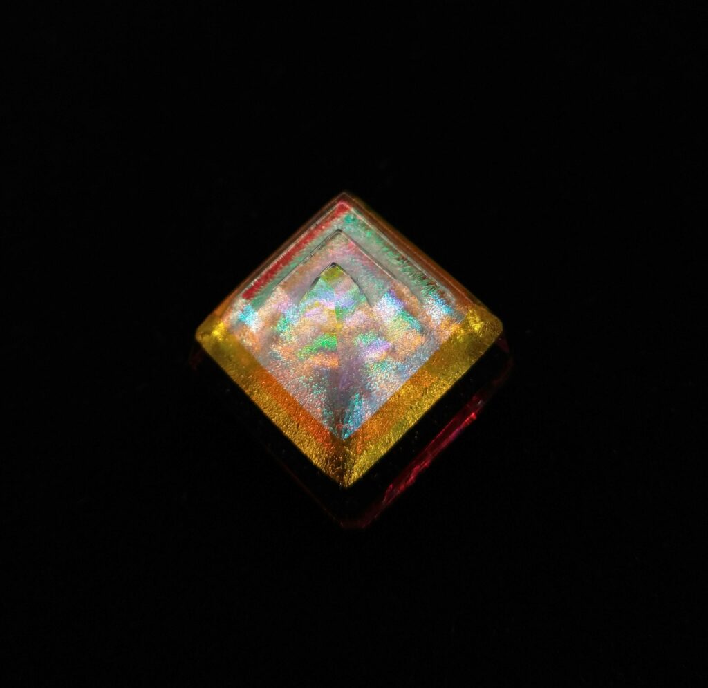 Glittering prismatic glass bead with an orange band on the rim.