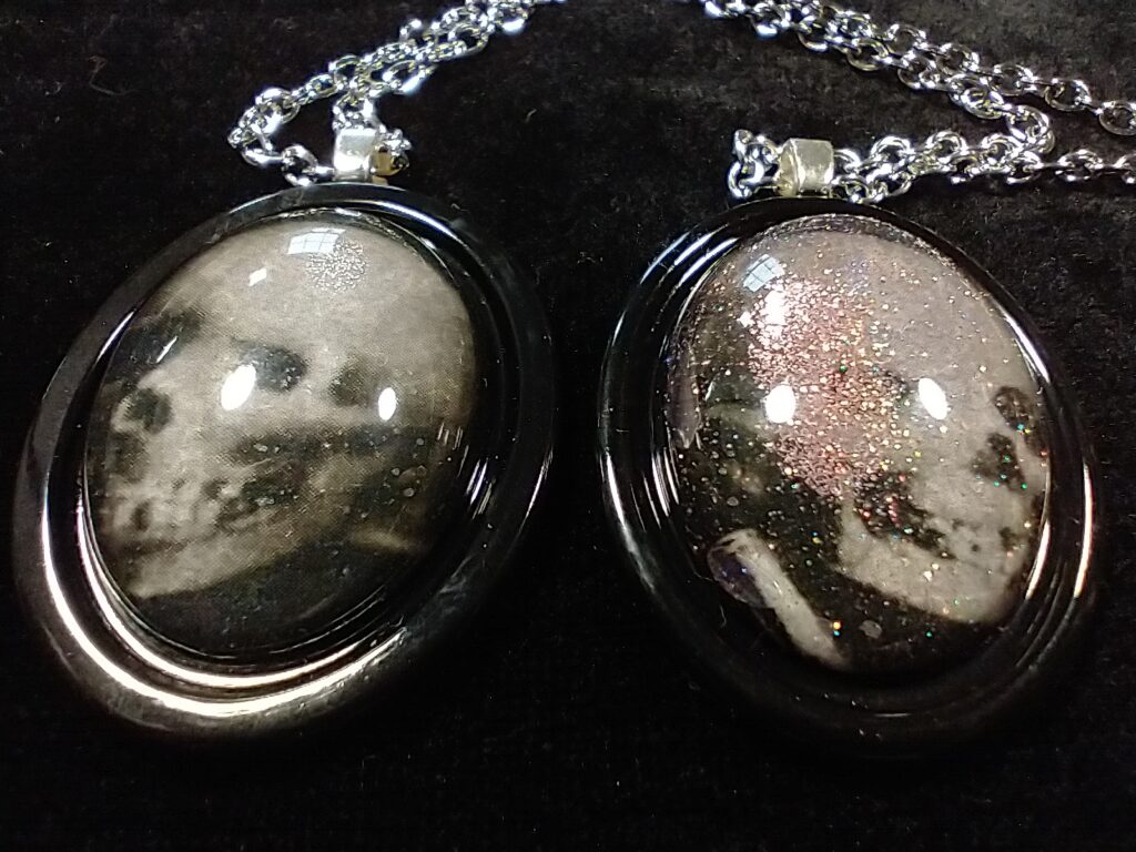 Two cabochons with creepy skulls and black frames.  One has a little glitter.