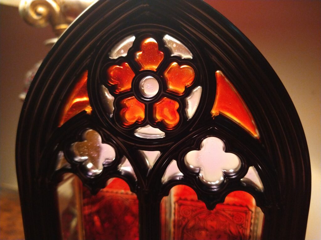 Top part of a resin cathedral window, in orange and red with black framing.