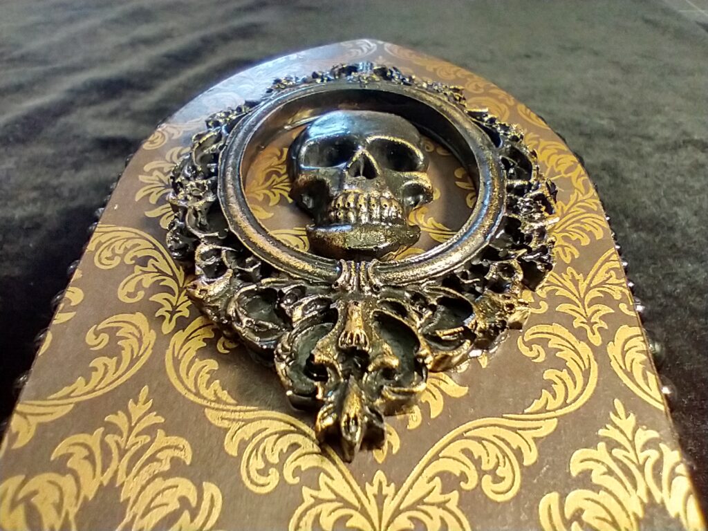 A coffin box with a framed skull on top.