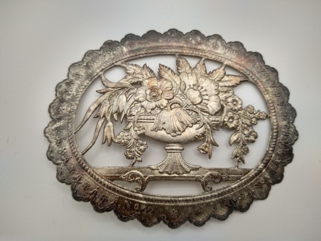 Embossed paper seal depicting a vase of flowers, foiled in silver.
