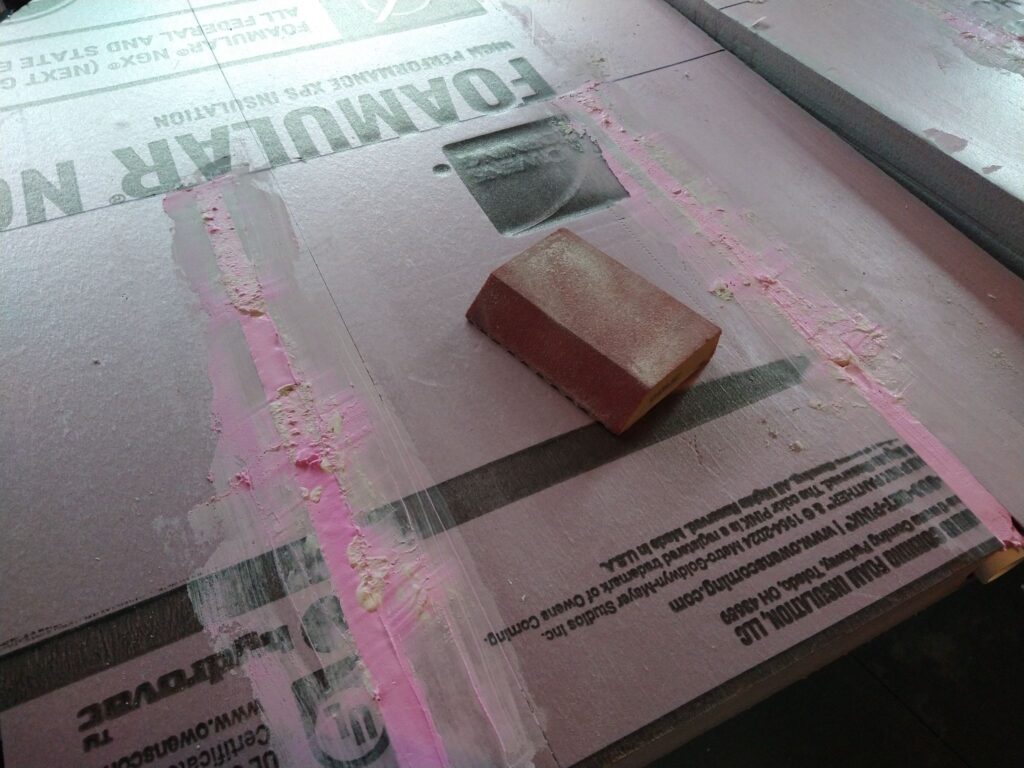 Back of a pink foam tombstone, with two channels filled with joint compound.