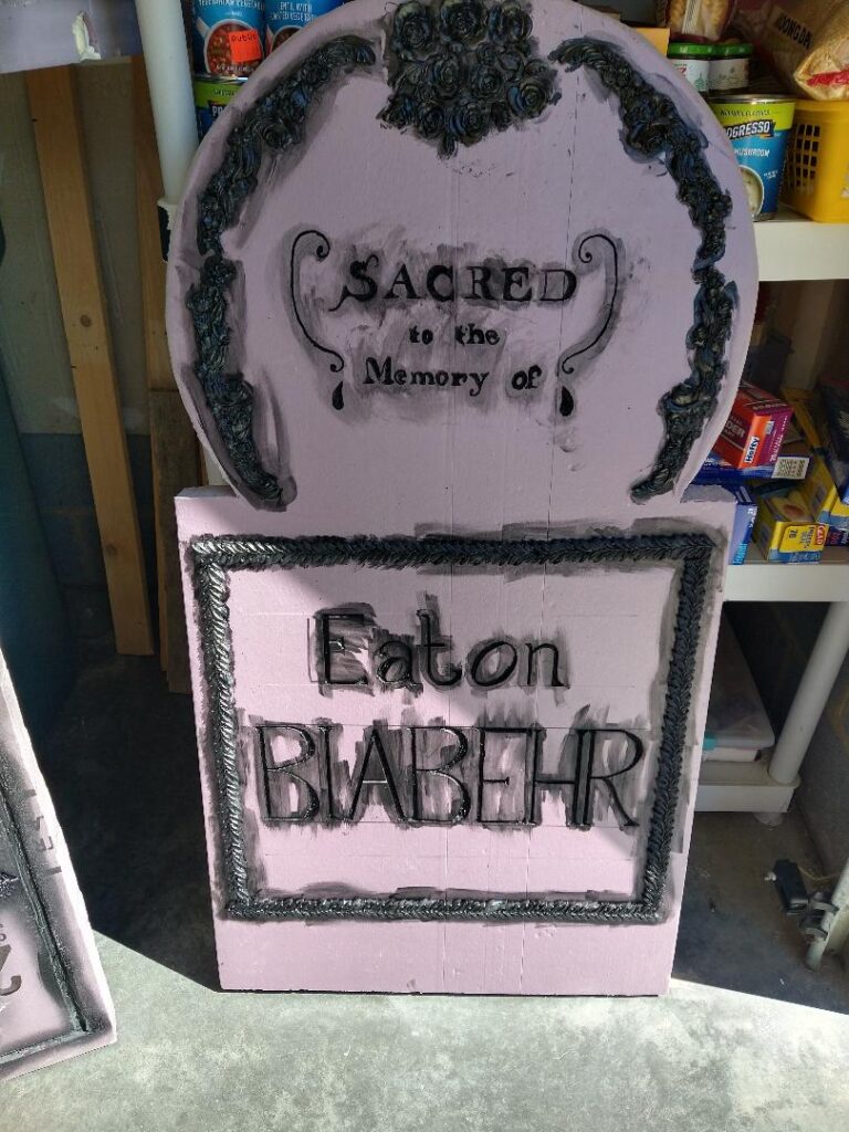 A pink foam tombstone smeared with black over all the lettering and details.