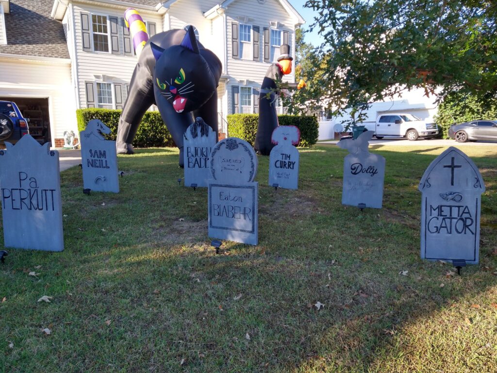 Seven stones stand in the corner of the yard. Behind them is a 12-foot inflatable cat, and a 10-foot inflatable reaper.